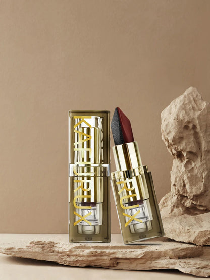 Luxury gold tube of Kafurux two-tone lipstick with matte and shimmer finish displayed on natural rock background